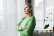© shurkin_son - Side view of sad thoughtful elderly female looking through window standing in living-room with folded arms,thinking of troubles and problems of her life and relationships with husband and children