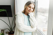 © shurkin_son - Indoor image of lonely abandoned aged caucasian female leaning her head against window, looking down with sad depressed facial expression, feeling loneliness, reflecting upon her life and youth