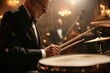 © Roman P. - Senior musician plays drums in dimly lit concert hall. Rhythm and passion embodied in every beat.
