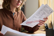 © pressmaster - Young woman working with domestic expenses and utility invoices, while sitting at desk and managing monthly budget