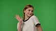 © kinomaster - Teenage girl posing at camera smiling and waving hand, positive expression, isolated on chroma key green screen studio background mockup.