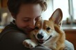 © Shelley - Happy man hugging his Corgi dog in a cozy, naturally lit kitchen with neutral tones and minimalistic style.