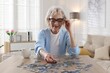 © New Africa - Woman solving jigsaw puzzle at wooden table indoors