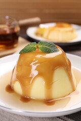 Wall Mural - delicious pudding with caramel sauce and mint on table, closeup