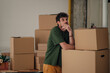 © Zamrznuti tonovi - Pensive man leaning on cardboard boxes in new home contemplates moving process