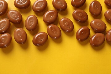Wall Mural - many tasty caramel candies on yellow background, flat lay. space for text