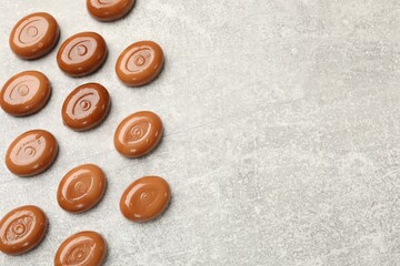 Wall Mural - many tasty caramel candies on grey table, flat lay. space for text