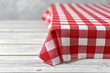 © Constantinos - Red and white checkered tablecloth draped on a wooden table. Rustic and charming, perfect for a picnic or casual dining.