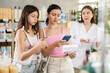 © JackF - Adult woman with girl shoppers scanning qr code for pill box with help of woman pharmacist in drugstore