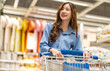 © Art_Photo - Asian woman shopping in home goods store smiling while pushing cart through bedding section, enjoying retail lifestyle, consumer behavior, weekend leisure, home decor at modern market