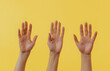 © Deny - Raising Human Hands Against a Yellow Background
