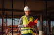 © Ljustina - Construction manager wearing safety helmet and vest is checking building progress on construction site