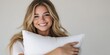 © Vergiliy - Smiling young woman holding white pillow against neutral background