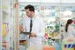 © ultramansk - man pharmacist checks and arranges medicines on pharmacy shelves, emphasizing precision and responsibility in healthcare services. The scene highlights the daily operations in a modern pharmacy.