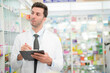 © ultramansk - man pharmacist checks and arranges medicines on pharmacy shelves, emphasizing precision and responsibility in healthcare services. The scene highlights the daily operations in a modern pharmacy.