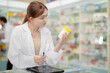 © ultramansk - A woman pharmacist inspects a medication bottle, ensuring accuracy in prescription filling. pharmacists in patient safety and careful medication handling. daily operations in a modern pharmacy.