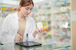 © ultramansk - A woman pharmacist inspects a medication bottle, ensuring accuracy in prescription filling. pharmacists in patient safety and careful medication handling. daily operations in a modern pharmacy.