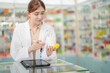 © ultramansk - A woman pharmacist inspects a medication bottle, ensuring accuracy in prescription filling. pharmacists in patient safety and careful medication handling. daily operations in a modern pharmacy.