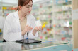 © ultramansk - A woman pharmacist inspects a medication bottle, ensuring accuracy in prescription filling. pharmacists in patient safety and careful medication handling. daily operations in a modern pharmacy.