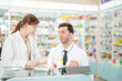 © ultramansk - team man and woman pharmacist inspects a medication bottle, ensuring accuracy in prescription filling. pharmacists in patient safety and careful medication handling. operations in retail pharmacy.