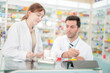 © ultramansk - team man and woman pharmacist inspects a medication bottle, ensuring accuracy in prescription filling. pharmacists in patient safety and careful medication handling. operations in retail pharmacy.