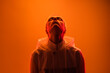 © kegfire - A person wearing a hoodie looks upwards, backlit in warm orange lighting. The image conveys a sense of emotion, introspection, and artistic expression, merging vibrant warm tones and dramatic