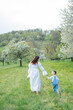 © Kristina89 - Young beautiful family walking in a field with blooming cherry trees. Dad, mom and little son playing in the garden outdoors.