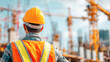 © romanets_v - Male construction worker overseeing urban building site with cranes and safety gear