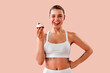 © HBS - Beautiful sporty girl holds a small low-calorie dessert, winks, and runs her tongue over her teeth as she gets ready to eat it. A playful and tempting concept for healthy treats or fitness nutrition.