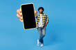 © ViDi Studio - Full body young Indian man wears yellow checkered shirt casual clothes hold use close up mobile cell phone with blank screen workspace area isolated on plain blue cyan background. Lifestyle concept.
