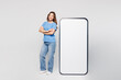 © ViDi Studio - Full body young woman wearing blue t-shirt casual clothes big huge blank screen mobile cell phone smartphone with area hold hands crossed folded isolated on plain white background. Lifestyle concept.