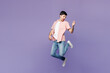 © ViDi Studio - Full body young man he wears pink shirt t-shirt casual clothes pretending play imaginary guitar while jump in air isolated on plain pastel light purple background studio portrait. Lifestyle concept.