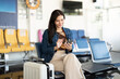 © Natee Meepian - Travel journey with a woman using a smartphone while sitting at the airport