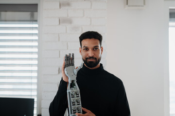 Portrait of young engineer holding robotic arm.