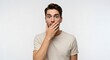 © phj.domingos - A young man looks stunned, covering his mouth with his hand against a white background.