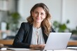 © MOON - Confident lawyer or executive woman working on laptop in bright office, smiling mature female professional manager looking at camera during workday