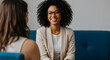 © abu - Smiling African American Woman in Beige Blazer Engages in Brightly Lit Conversation on Blue Sofa