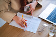 © Studio Marmellata - An Arab woman reviews financial documents at her desk. She uses a pencil and ruler to analyze the data, with a laptop and glasses nearby.