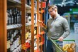 © Serhii - A man takes alcoholic drinks from the supermarket shelf. Shopping for alcohol in the store