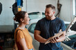 © peopleimages.com - Woman, mechanic and sign agreement in auto repair shop, invoice and service for car maintenance. Female person, clipboard and customer for vehicle transaction, contract and laugh in garage for quote