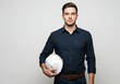 © Vooglo.com - Young man in blue shirt holding a white hard hat against a plain background