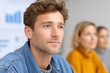 © venusvi - A focused young man engages in a discussion during a business meeting, showcasing professionalism and teamwork in a modern office setting.