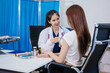 © NanSan - An Asian woman sits at a table consulting with a female doctor. They discuss her symptoms related to stress and depression. The doctor listens attentively and recommends treatment and medication