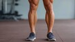 © Sawyer0 - Close-up of muscular human legs on gym floor shows defined anatomy, highlighting strength and physical conditioning.