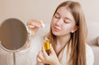 © st.kolesnikov - Girl applying yellow facial serum from dropper bottle during her daily beauty routine.