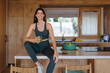 © Westend61 - Woman in sportswear sitting on kitchen counter with green juice