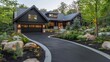 © Traipop - A luxurious modern black house with a long winding driveway sits led amongst lush landscaping and large rocks at dusk.