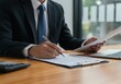 © PP Creative - Businessman signing document at desk with laptop and calculator