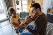 © NDABCREATIVITY - Young man musician teaching a teen girl to play violin. Education music instrument happiness concept
