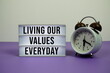 © may1985 - Living our values everyday text on LED lightbox with alarm clock on purple background